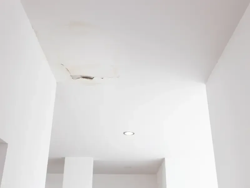 Water stains and cracked paint along a ceiling soffit after a leak