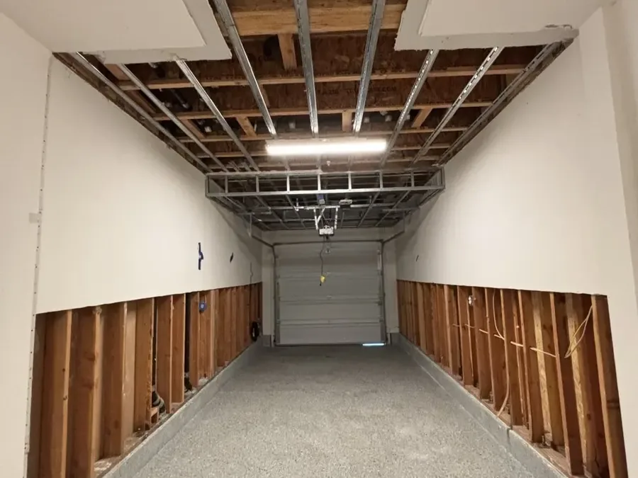 Garage with drywall flood cuts along both walls after a water heater leak