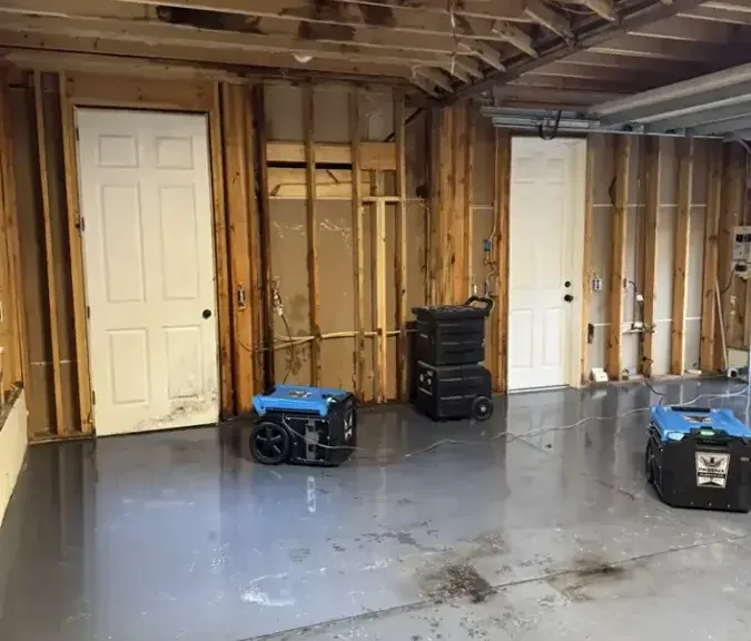 Dehumidifiers drying a gutted room with the lower walls opened after water damage
