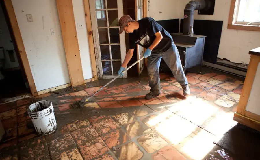 Mud and runoff being scraped off a tile floor after a flash flood