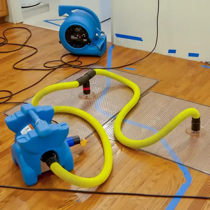 Air mover, yellow hoses and mats on a hardwood floor during a structured dry-out