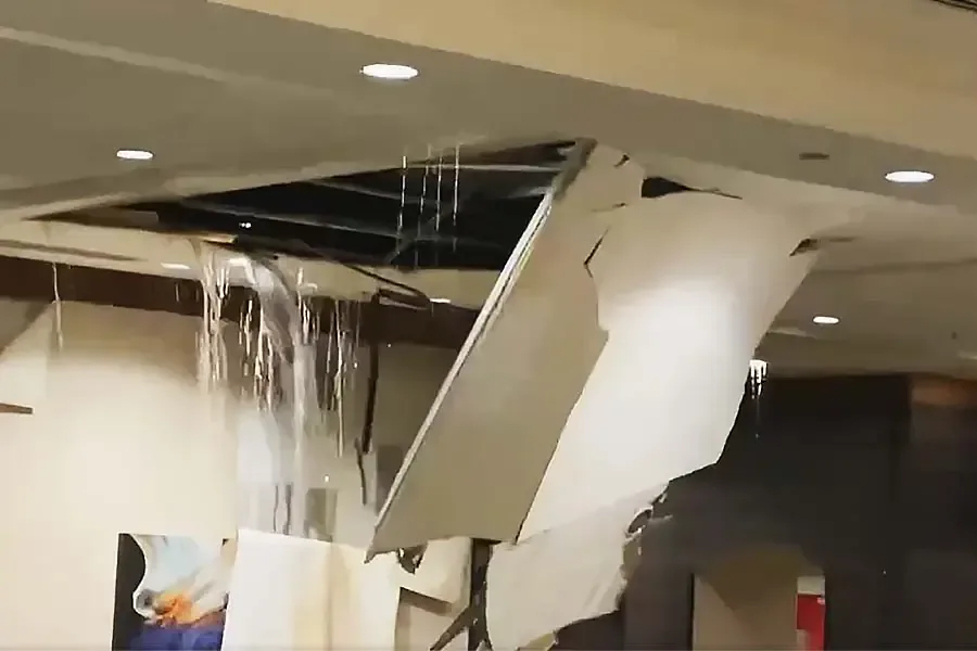 Water pouring through a collapsed ceiling from a leak on the floor above