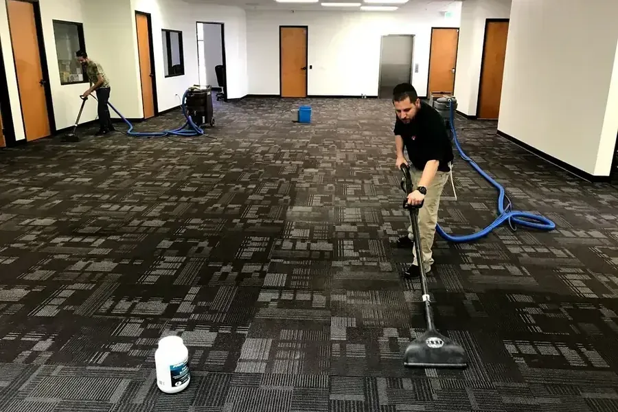Technician extracting water from carpet in a large open office space