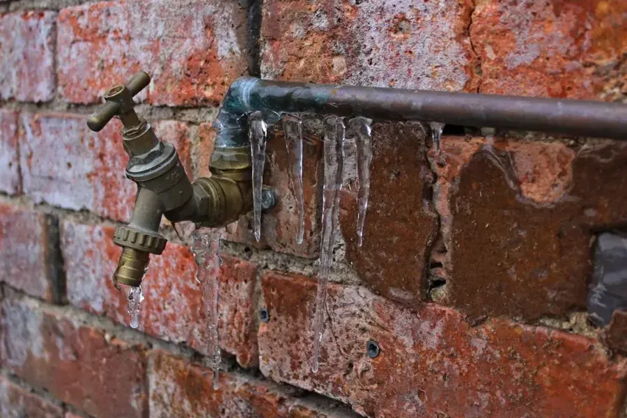 Ice coating an outdoor hose spigot on a brick wall during a hard freeze